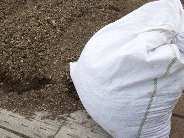 Garden soil and a white fertilizer sack – materials for grow bag tomato cultivation