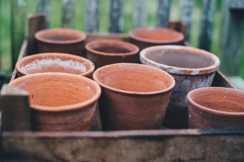 A collection of terracotta pots arranged in a wooden crate, used for gardening and planting.